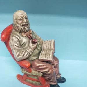 Figura anciano leyendo en mecedora